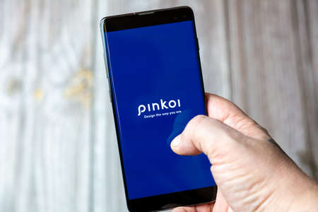 02-15-2021 Portsmouth, Hampshire, UK A mobile phone or cell phone being held in a hand with the Pinkoi app open on screenのeditorial素材