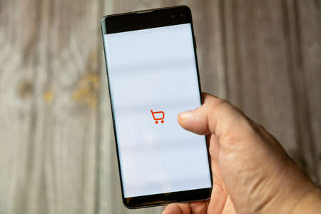 02-15-2021 Portsmouth, Hampshire, UK A mobile phone or cell phone being held in a hand with the sainsbury's shopping app open on screenのeditorial素材