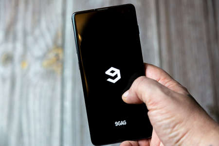 02-15-2021 Portsmouth, Hampshire, UK A mobile phone or cell phone being held in a hand with the 9gag app open on screenのeditorial素材