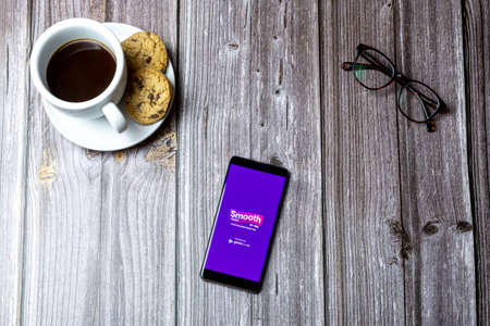 02-15-2021 Portsmouth, Hampshire, UK A mobile phone or cell phone laid on a wooden table with the smooth radio app open on screenのeditorial素材