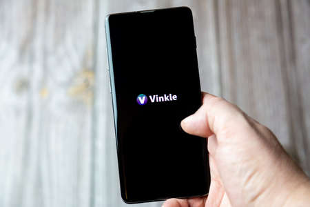02-15-2021 Portsmouth, Hampshire, UK A mobile phone or cell phone being held in a hand with the Vinkle app open on screenのeditorial素材