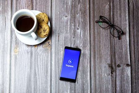 02-15-2021 Portsmouth, Hampshire, UK A mobile phone or cell phone laid on a wooden table with the Triplens app open on screenのeditorial素材