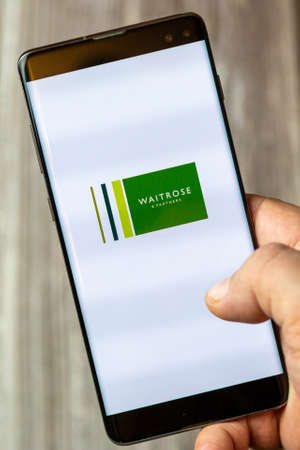 02-15-2021 Portsmouth, Hampshire, UK A mobile phone or cell phone being held in a hand with the Waitrose shopping app open on screenのeditorial素材
