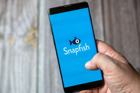 02-15-2021 Portsmouth, Hampshire, UK A mobile phone or cell phone being held in a hand with the snapfish app open on screenのeditorial素材