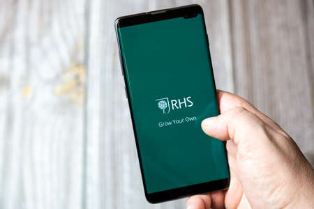 02-15-2021 Portsmouth, Hampshire, UK A mobile phone or cell phone being held in a hand with the RHS app open on screenのeditorial素材