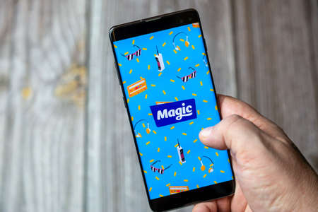 02-15-2021 Portsmouth, Hampshire, UK A mobile phone or cell phone being held in a hand with the Magic Radio app open on screenのeditorial素材