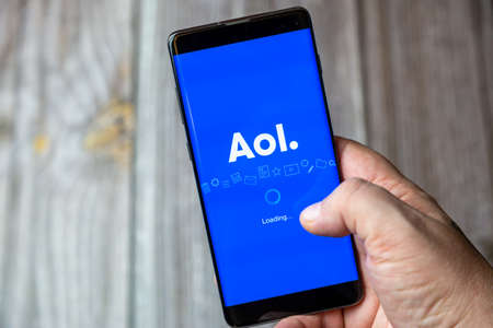 02-15-2021 Portsmouth, Hampshire, UK A mobile phone or cell phone being held in a hand with the AOL app open on screenのeditorial素材