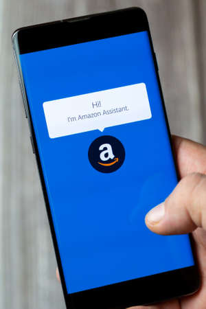 02-15-2021 Portsmouth, Hampshire, UK A mobile phone or cell phone being held in a hand with the Amazon assistant app open on screenのeditorial素材