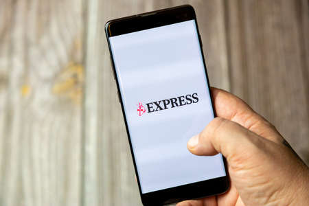 02-15-2021 Portsmouth, Hampshire, UK A mobile phone or cell phone being held in a hand with the Express news app open on screenのeditorial素材