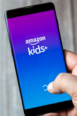 02-15-2021 Portsmouth, Hampshire, UK A mobile phone or cell phone being held in a hand with the amazon kids plus app open on screenのeditorial素材