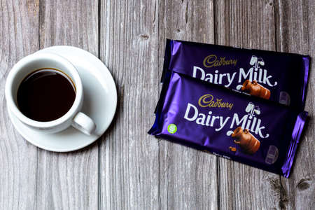 02-24-2021 Portsmouth, Hampshire, UK Two Bars of Cadbury Dairy Milk chocolate lad on a wooden table next to a cup of coffeeのeditorial素材