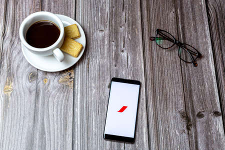 02-24-2021 Portsmouth, Hampshire, UK A mobile phone or cell phone on a wooden table with the Air France app open next to a coffee and glassesのeditorial素材