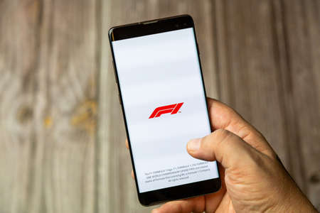 02-24-2021 Portsmouth, Hampshire, UK A mobile phone or cell phone being held by a hand with the F1 or Formula one app open on screenのeditorial素材
