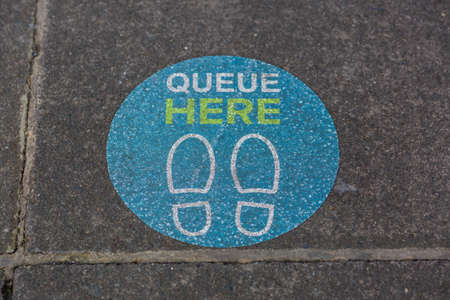 A sign on the pavement outside a supermarket showing people where to stand to keep social distance during the  pandemicの写真素材