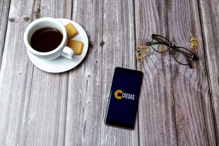 03-03-2021 Portsmouth, Hampshire, UK A mobile phone or cell phone laid on a wooden table with the Credas ID app open next to a coffeeのeditorial素材