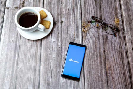 03-03-2021 Portsmouth, Hampshire, UK A mobile phone or cell phone laid on a wooden table with the Loveholidays app open next to a coffeeのeditorial素材