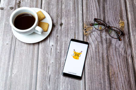 03-03-2021 Portsmouth, Hampshire, UK A mobile phone or cell phone laid on a wooden table with the Lingodeer app open next to a coffeeのeditorial素材