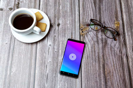03-03-2021 Portsmouth, Hampshire, UK A mobile phone or cell phone laid on a wooden table with the Ripl social media app open next to a coffeeのeditorial素材