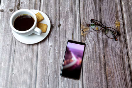 03-03-2021 Portsmouth, Hampshire, UK A mobile phone or cell phone laid on a wooden table with the Absher app open next to a coffeeのeditorial素材