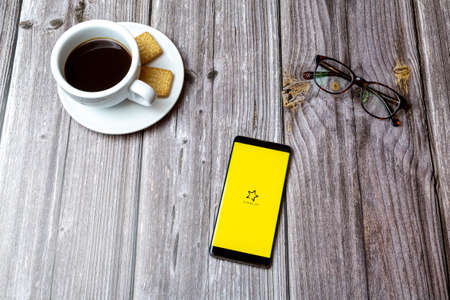 03-03-2021 Portsmouth, Hampshire, UK A mobile phone or cell phone laid on a wooden table with the TUI magic life app open next to a coffeeのeditorial素材