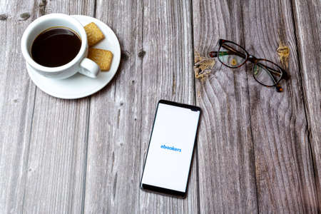 03-03-2021 Portsmouth, Hampshire, UK A mobile phone or cell phone laid on a wooden table with the eBookers app open next to a coffeeのeditorial素材