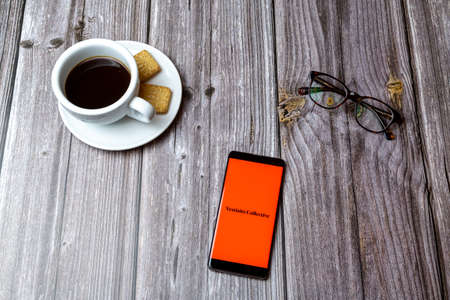 03-03-2021 Portsmouth, Hampshire, UK A mobile phone or cell phone laid on a wooden table with the Vestiaire collective app open next to a coffeeのeditorial素材