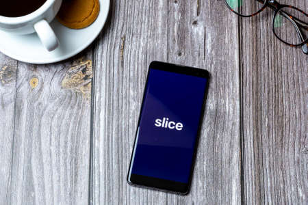 03-10-2021 Portsmouth, Hampshire, UK A Mobile phone or cell phone laid on a wooden table with the Slice pay later app open on screenのeditorial素材