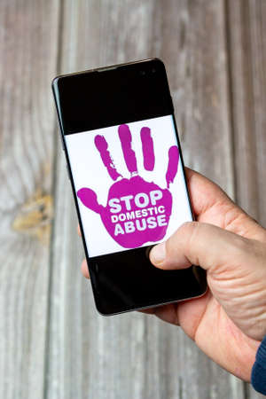 03-10-2021 Portsmouth, Hampshire, UK A Mobile phone or cell phone being held in a hand with the stop domestic abuse open on screenのeditorial素材