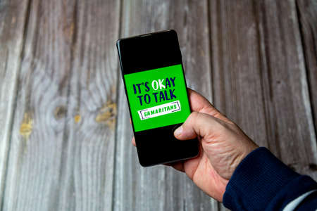 03-10-2021 Portsmouth, Hampshire, UK A Mobile phone or cell phone being held in a hand with the Samaritans open on screenのeditorial素材