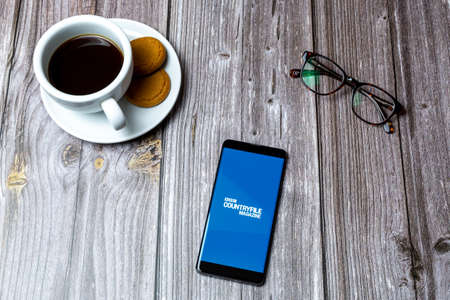 03-10-2021 Portsmouth, Hampshire, UK A Mobile phone or cell phone laid on a wooden table with the Countryfile magazine app open on screenのeditorial素材