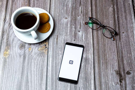 03-10-2021 Portsmouth, Hampshire, UK A Mobile phone or cell phone laid on a wooden table with the square payment app open on screenのeditorial素材