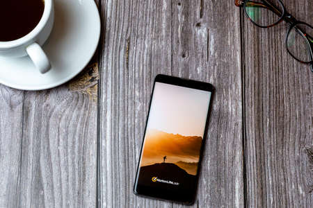 02/10/2021 Portsmouth, Hampshire, UK A mobile phone or cell phone laid on a wooden table with the Norton Life lock app open on screen next to a coffeeのeditorial素材