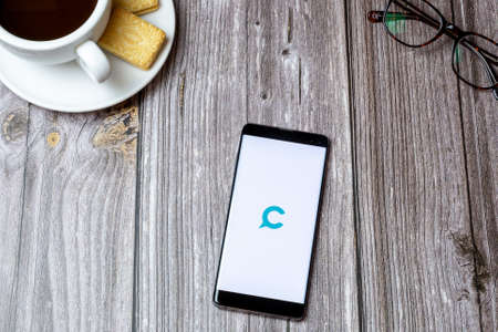 02-24-2021 Portsmouth, Hampshire, UK A mobile phone or cell phone on a wooden table with the Cinchshare app open next to a coffee and glassesのeditorial素材