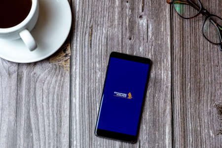 02/10/2021 Portsmouth, Hampshire, UK A mobile phone or cell phone laid on a wooden table with the Singapore airlines app open on screenのeditorial素材
