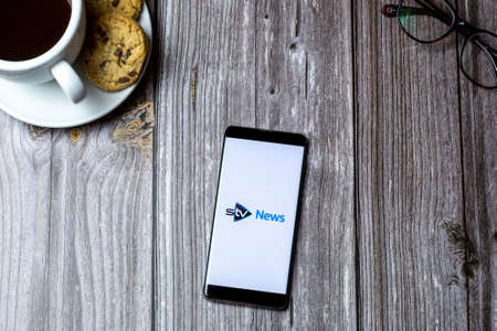 02-15-2021 Portsmouth, Hampshire, UK A mobile phone or cell phone laid on a wooden table with the STV news app open on screenのeditorial素材