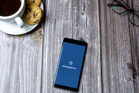 02-15-2021 Portsmouth, Hampshire, UK A mobile phone or cell phone laid on a wooden table with the Digidentity app open on screenのeditorial素材