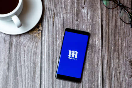 02/10/2021 Portsmouth, Hampshire, UK A mobile phone or cell phone laid on a wooden table with the daily Mail online app open on screenのeditorial素材