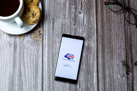 02-15-2021 Portsmouth, Hampshire, UK A mobile phone or cell phone laid on a wooden table with the Capital FM radio app open on screenのeditorial素材