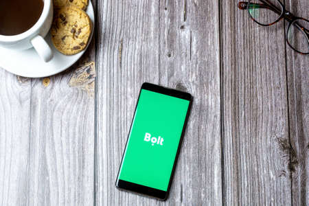 02-15-2021 Portsmouth, Hampshire, UK A mobile phone or cell phone laid on a wooden table with the Bolt Messaging app open on screenのeditorial素材