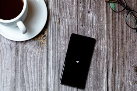 02/10/2021 Portsmouth, Hampshire, UK A mobile phone or cell phone laid on a wooden table with the JD app open on screen next to a coffeeのeditorial素材
