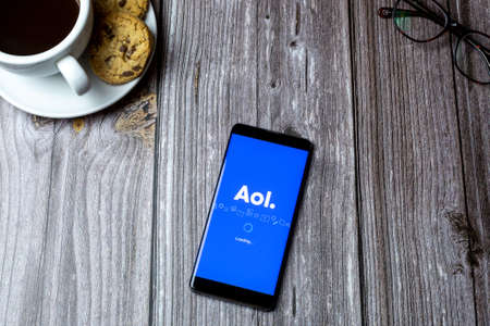 02-15-2021 Portsmouth, Hampshire, UK A mobile phone or cell phone laid on a wooden table with the AOL app open on screenのeditorial素材