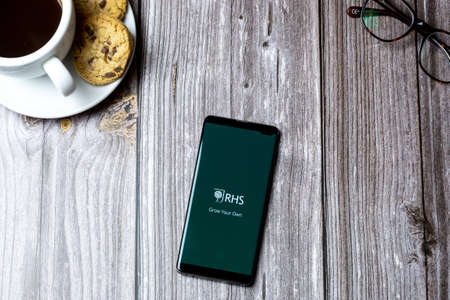 02-15-2021 Portsmouth, Hampshire, UK A mobile phone or cell phone laid on a wooden table with the RHS app open on screenのeditorial素材