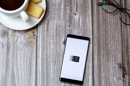 02-24-2021 Portsmouth, Hampshire, UK A mobile phone or cell phone on a wooden table with the John Lewis and Partners app open next to a coffeのeditorial素材
