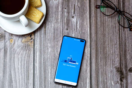 02-24-2021 Portsmouth, Hampshire, UK A mobile phone or cell phone on a wooden table with the Cisco Business app open next to a coffee and glassesのeditorial素材
