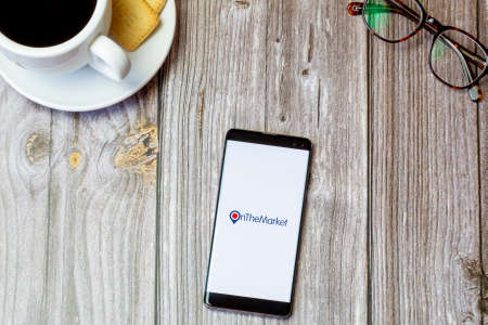 03-22-2021 Portsmouth, Hampshire, UK A mobile phone or cell phone laid on a wooden table with the On the market app open on screenのeditorial素材