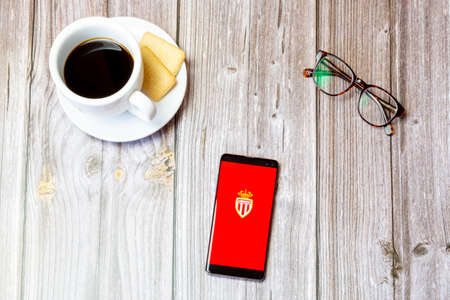 03-22-2021 Portsmouth, Hampshire, UK A mobile phone or cell phone laid on a wooden table with the AS Monaco app open on screenのeditorial素材
