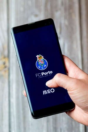 03-22-2021 Portsmouth, Hampshire, UK A mobile phone or cell phone being held in a hand with the FC Porto app open on screenのeditorial素材