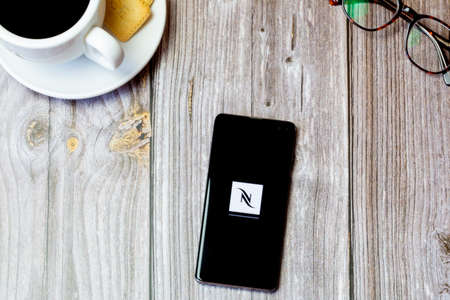 03-22-2021 Portsmouth, Hampshire, UK A mobile phone or cell phone laid on a wooden table with the Nespresso app open on screenのeditorial素材
