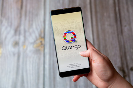03-22-2021 Portsmouth, Hampshire, UK A mobile phone or cell phone being held in a hand with the Qlango app open on screenのeditorial素材