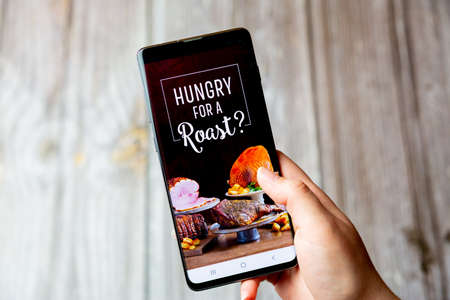 03-22-2021 Portsmouth, Hampshire, UK A mobile phone or cell phone being held in a hand with the Toby Carvery app open on screenのeditorial素材